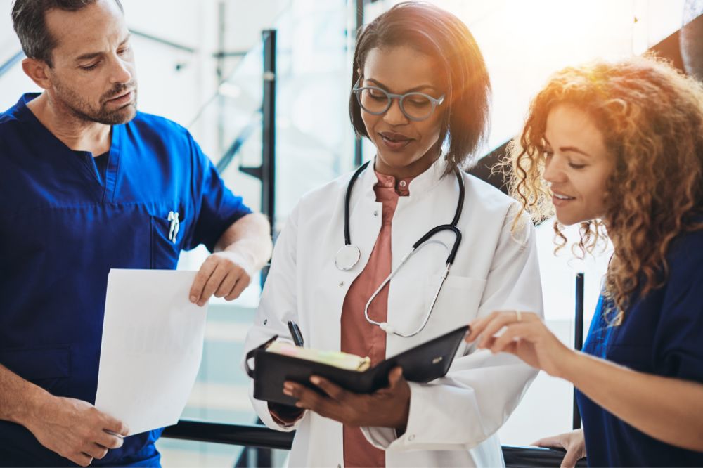 three medical practitioners reviewing documents together